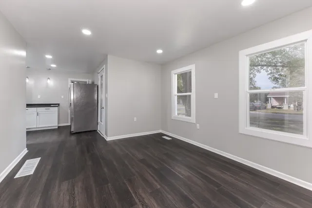 an empty room with wooden floor and windows