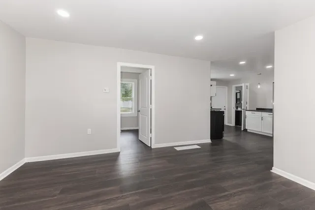 a view of a big room with wooden floor and a kitchen