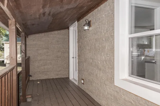 a view of a hallway with wooden floor and a bathroom