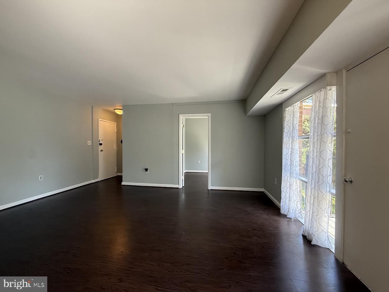 3419 University Boulevard West, Unit 203 Kensington, MD 20895 - Photo 5 of 25 an empty room with wooden floor and windows