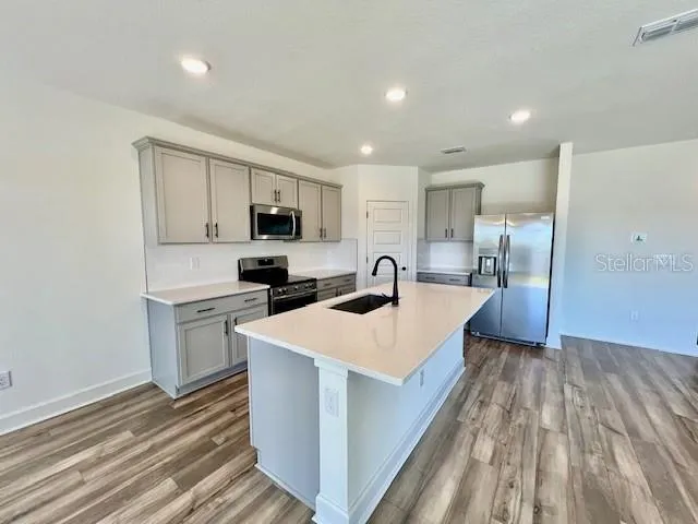 a large kitchen with stainless steel appliances a sink and a stove