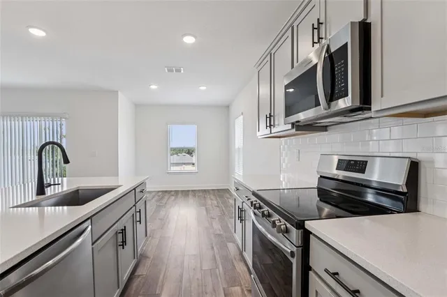 a kitchen with stainless steel appliances granite countertop a stove microwave and sink