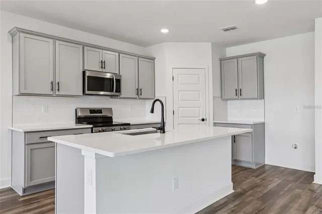 a kitchen with stainless steel appliances a stove microwave and sink