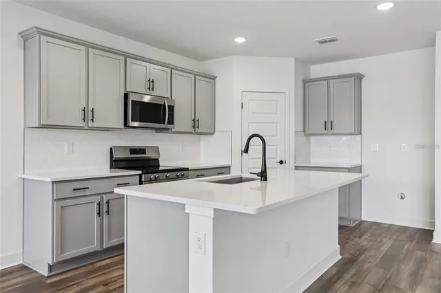 a kitchen with stainless steel appliances granite countertop a stove a sink and a microwave