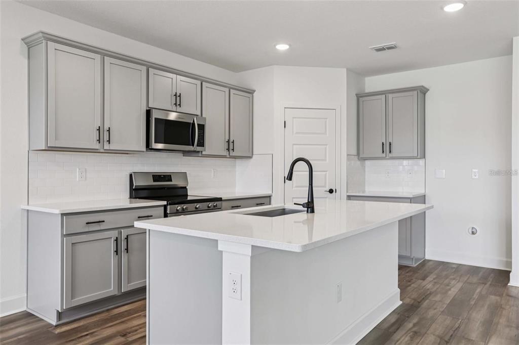 13112 Siam Drive Spring Hill, FL 34609 - Photo 19 of 46 a kitchen with stainless steel appliances granite countertop a stove a sink and a microwave
