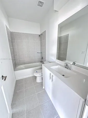 a bathroom with a bathtub shower sink mirror vanity and toilet