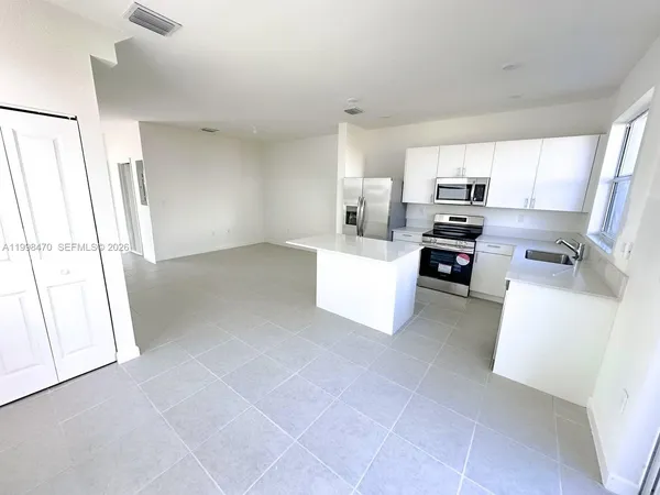 a view of kitchen with microwave a stove and white cabinets