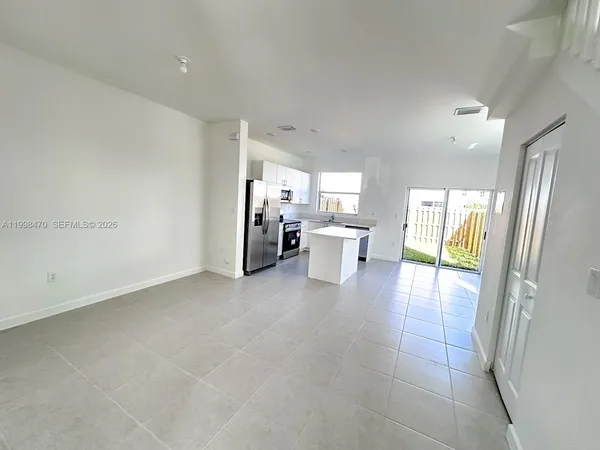 a open hall with stainless steel appliances granite countertop a refrigerator and a sink