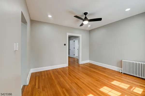 a view of an empty room with window and chandelier fan