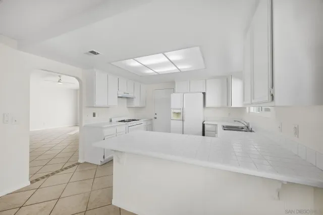 a large white kitchen with a sink and cabinets
