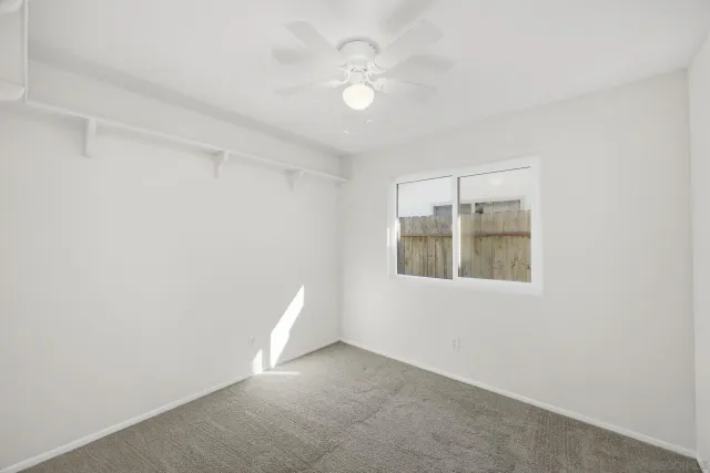 an empty room with a window and a fan