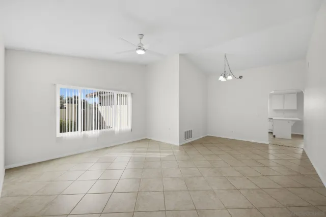 an empty room with chandelier fan and windows