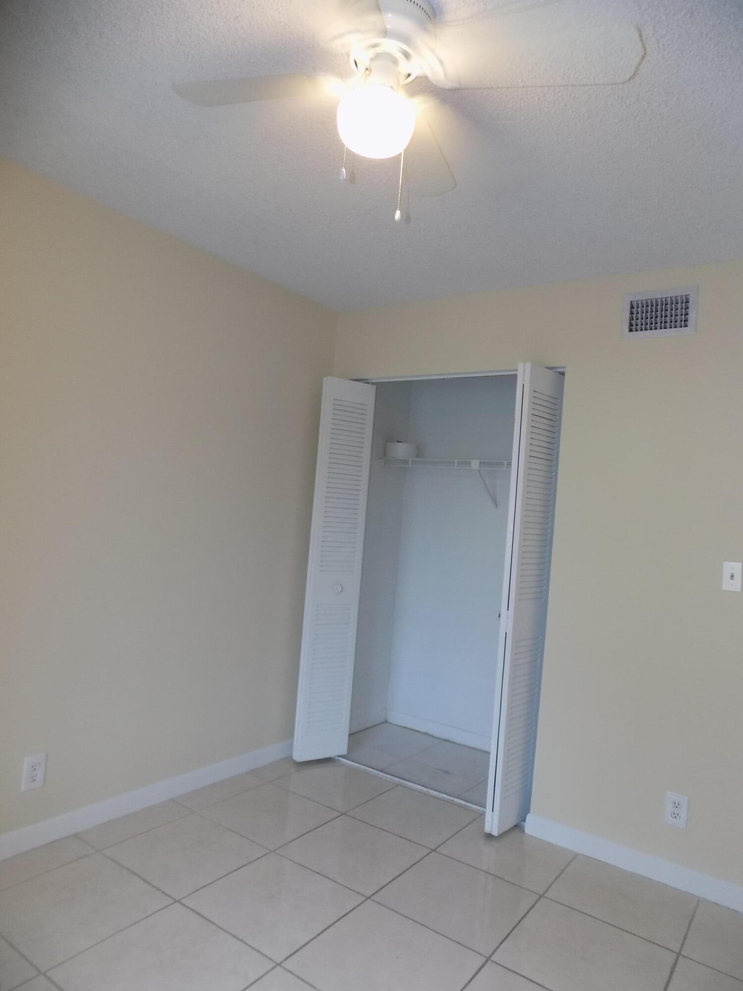 4181 South 57th Avenue, Unit B Greenacres, FL 33463 - Photo 18 of 25 an empty room with a chandelier fan and closet area