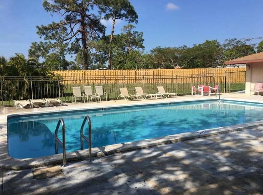 4181 South 57th Avenue, Unit B Greenacres, FL 33463 - Photo 23 of 25 a view of a lake with a bench and trees in the background