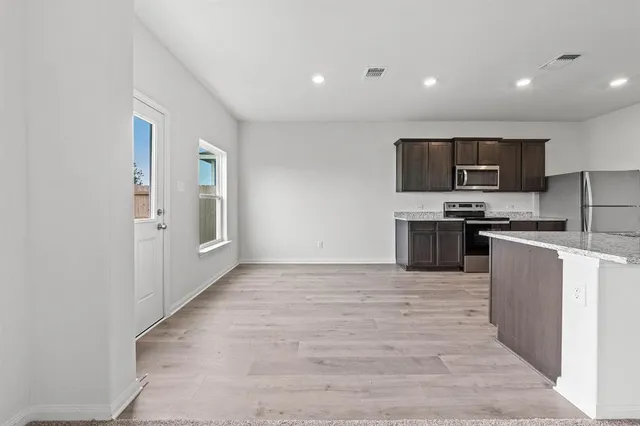 a view of kitchen with stainless steel appliances granite countertop a refrigerator and a stove top oven