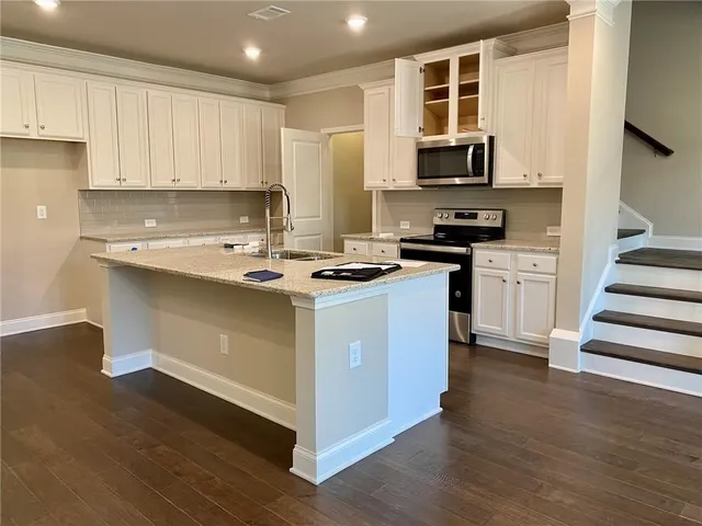 a view of kitchen with granite countertop stainless steel appliances and wooden floor