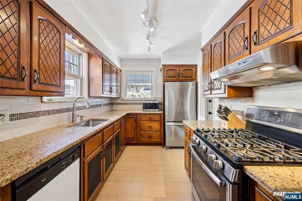53 Forest Hill Road West Orange, NJ 07052 - Photo 14 of 40 a kitchen with stainless steel appliances granite countertop a stove a sink dishwasher and refrigerator with wooden cabinets