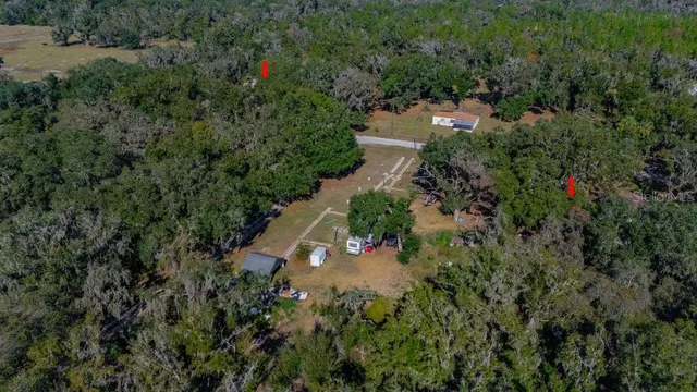 an aerial view of residential house with outdoor space and trees all around