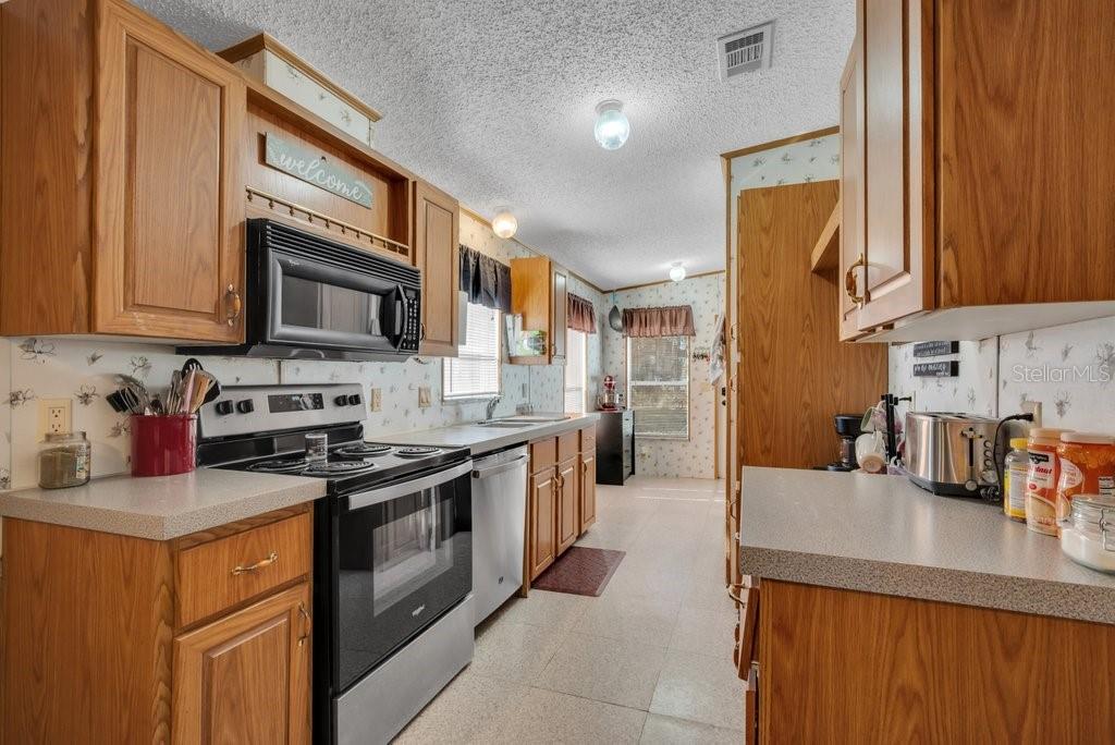 415 Hal Colding Road Lithia, FL 33547 - Photo 62 of 73 a kitchen with stainless steel appliances granite countertop a stove a sink dishwasher and a microwave oven with cabinets