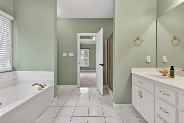 a spacious bathroom with a granite countertop sink a mirror and a bathtub