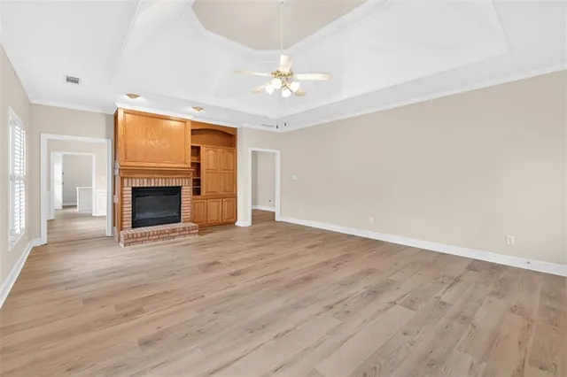 a view of an empty room with wooden floor fireplace and a window
