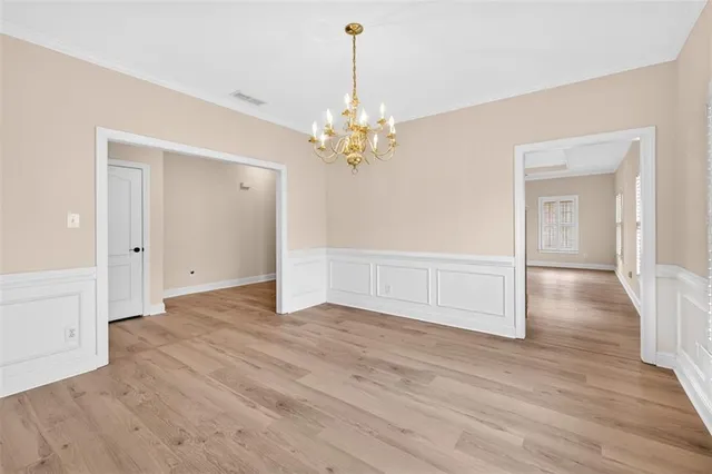 a view of an empty room with wooden floor and a ceiling fan