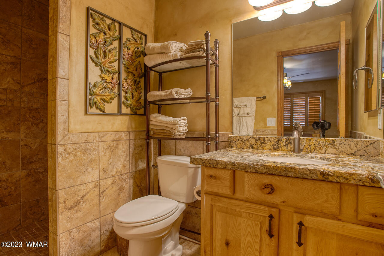 1911 North Bison Ridge Trail, Unit 10 Show Low, AZ 85901 - Photo 13 of 17 a bathroom with a granite countertop toilet sink and mirror