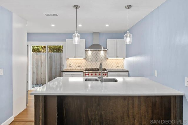 a kitchen with kitchen island a sink stainless steel appliances and a chandelier