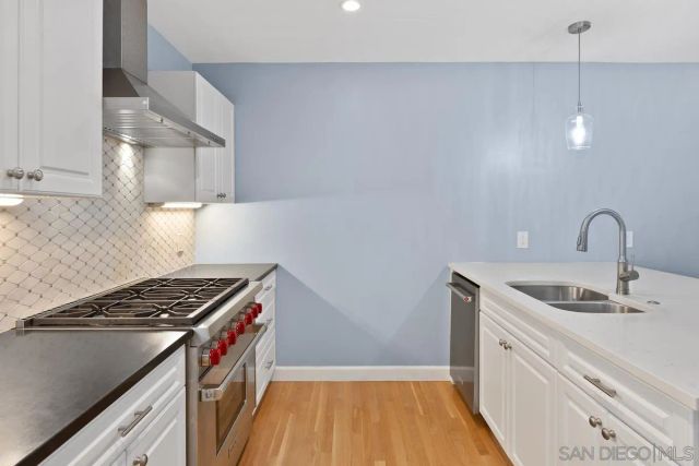 a kitchen that has a sink and a stove with wooden floor