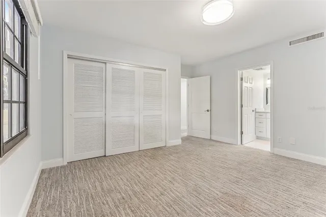 an empty room with windows and chandelier fan