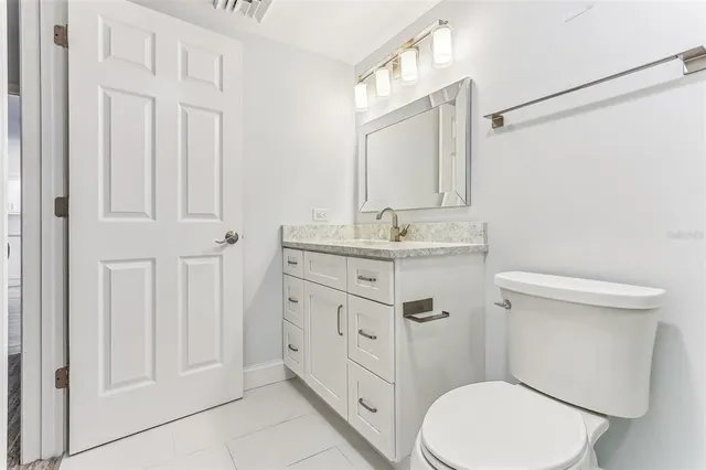 a bathroom with a granite countertop toilet sink and mirror