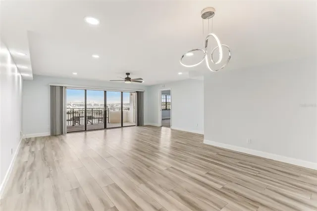 a view of an empty room with wooden floor and windows
