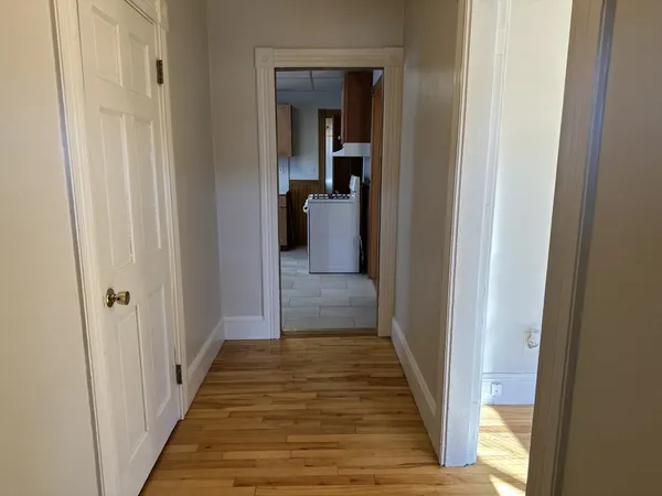 a view of a hallway with wooden floor and a bathroom