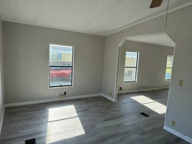 an empty room with wooden floor and windows