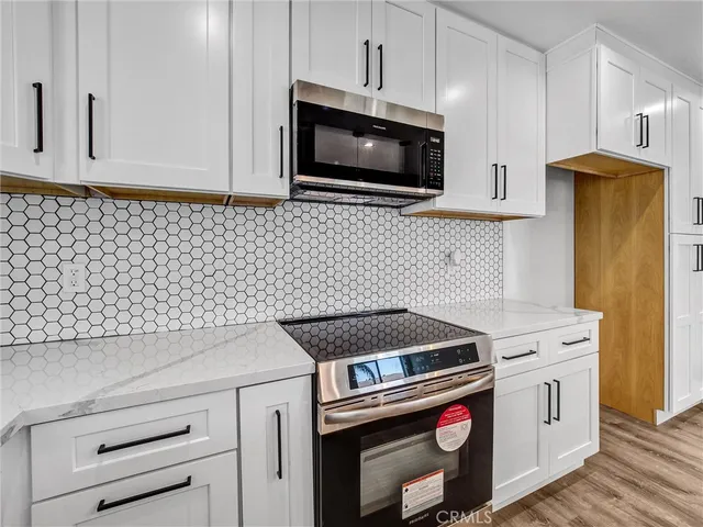 a kitchen with granite countertop white cabinets and stainless steel appliances