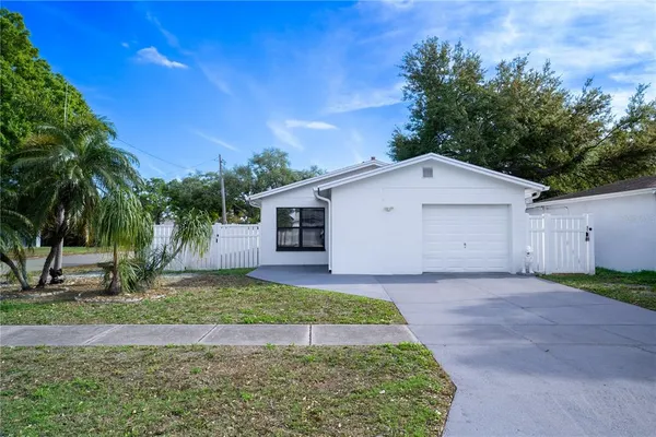 a view of a white house next to a yard with palm trees