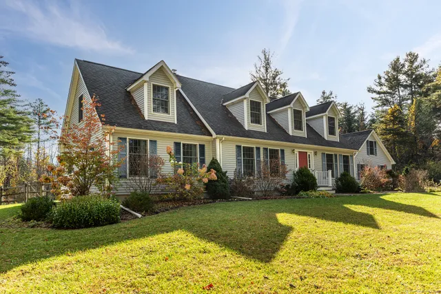 a front view of a house with a garden and trees