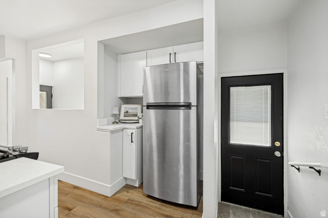662 29th Street Ogden, UT 84403 - Photo 7 of 23 Kitchen area featuring a stainless steel refrigerator, white cabinetry with dark hardware, and wood-finish flooring