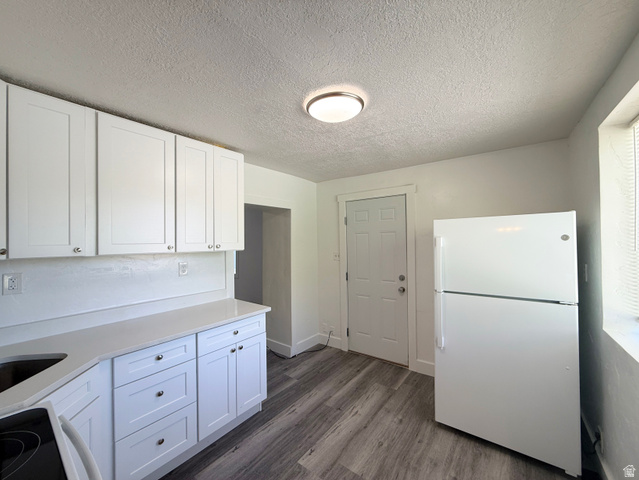 548 27th Street Ogden, UT 84403 - Photo 6 of 13 Kitchen featuring freestanding refrigerator, white cabinetry, a textured ceiling, black range with electric stovetop, and dark wood-style flooring