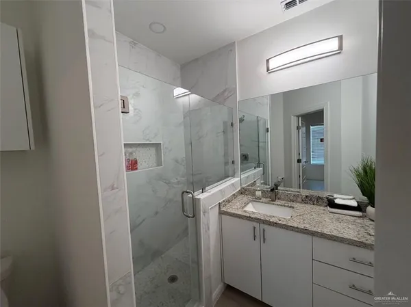 a bathroom with a granite countertop sink a mirror and a shower