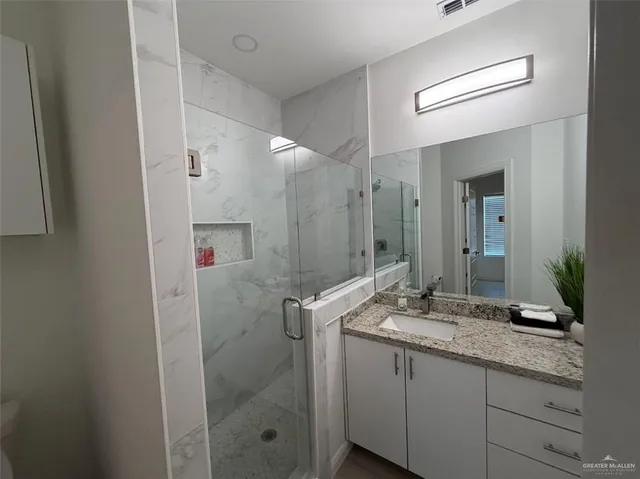 a bathroom with a granite countertop sink a mirror and a shower
