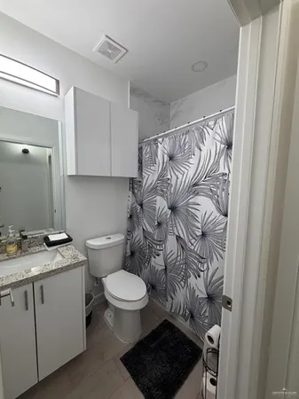 a bathroom with a granite countertop toilet sink and mirror