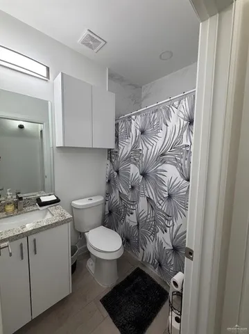 a bathroom with a granite countertop toilet sink and mirror