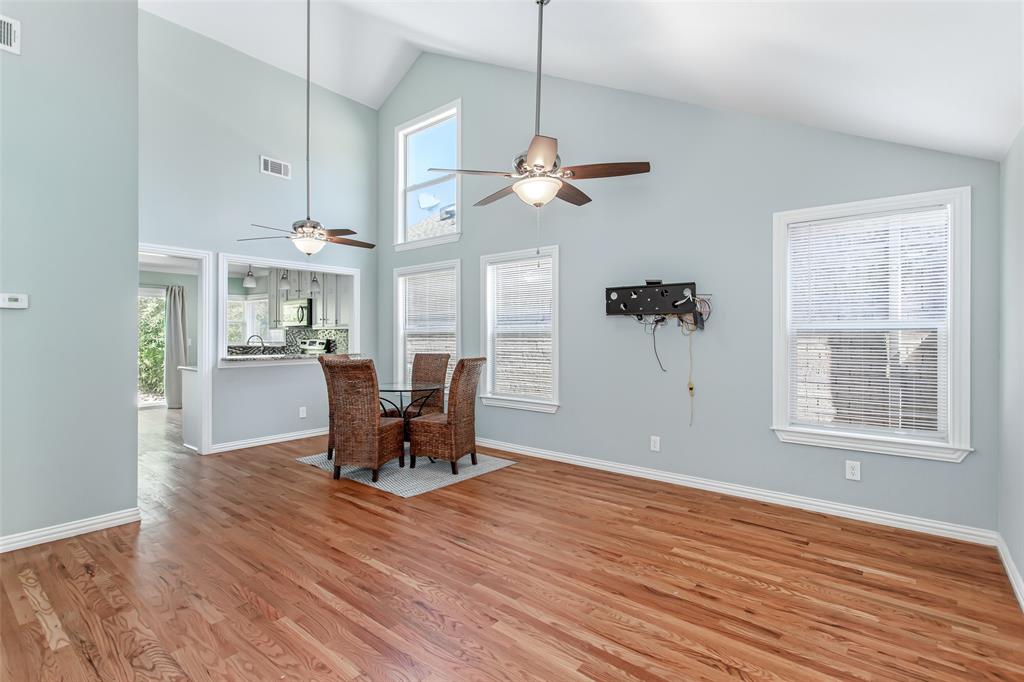 Open-concept layout combining the living and dining areas, soaring ceilings, modern ceiling fans, and abundant natural light.