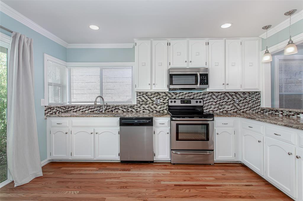 4139 Rosser Square Dallas, TX 75244 - Photo 13 of 34 Light-filled kitchen featuring granite countertops, white cabinetry, stainless steel appliances, and rich hardwood flooring for a timeless and elegant look.