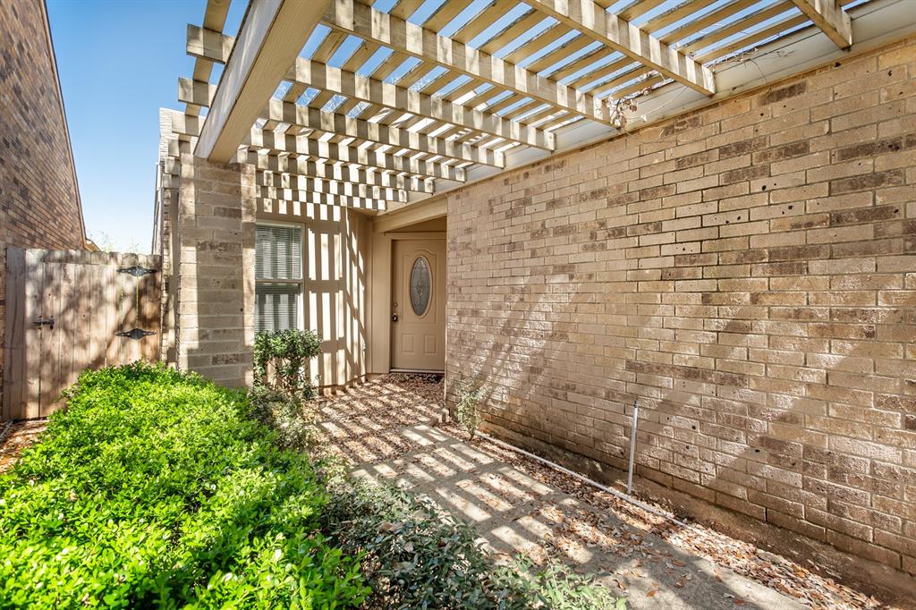 4139 Rosser Square Dallas, TX 75244 - Photo 29 of 34 Tranquil courtyard-style entrance featuring lush landscaping, a shaded pergola, and a private front door—perfect for added charm and privacy.