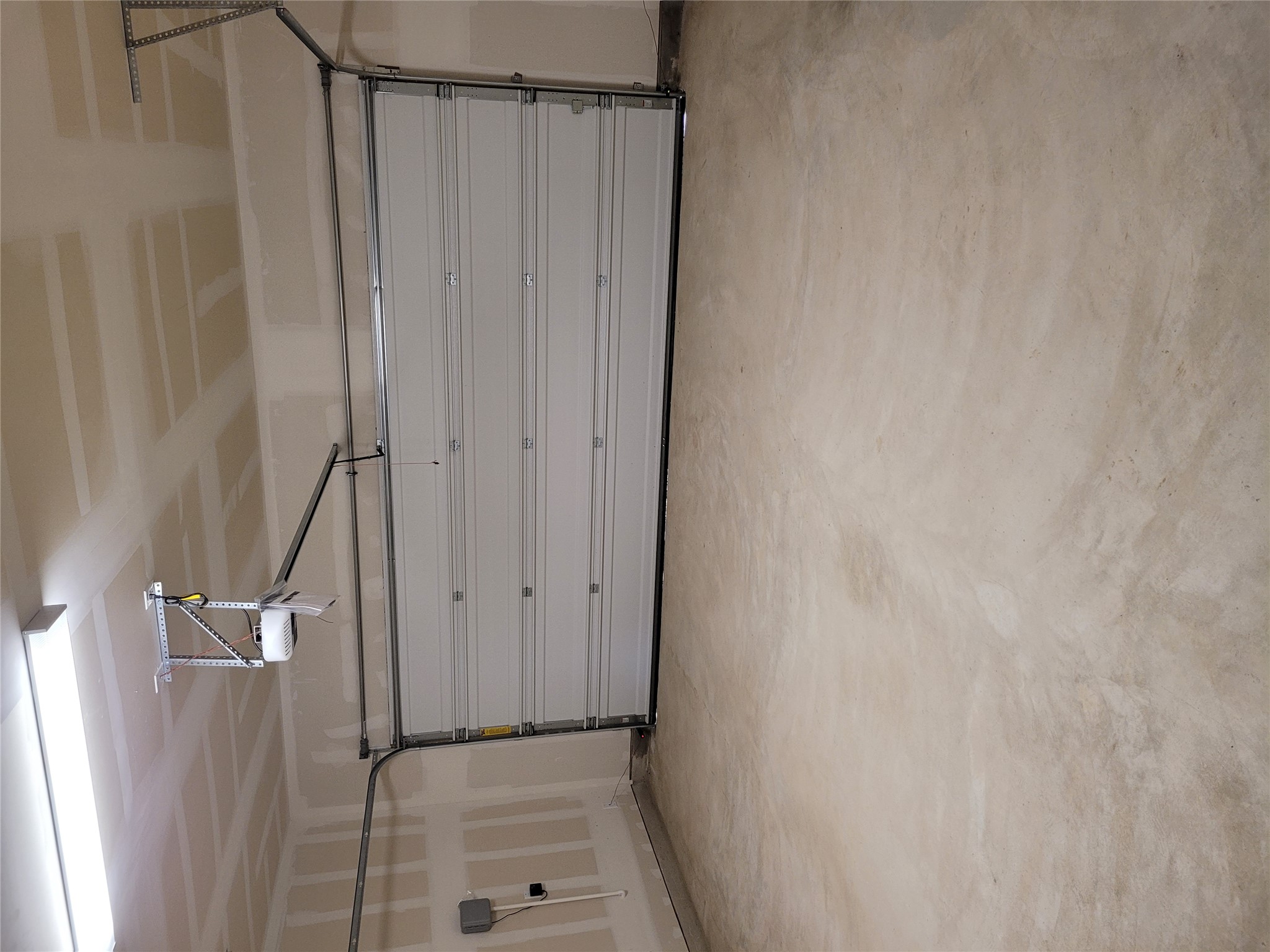 131 Wild Wind Cove Jarrell, TX 76537 - Photo 6 of 26 Spacious garage with a light-colored concrete floor, automatic garage door opener, and overhead fluorescent lighting