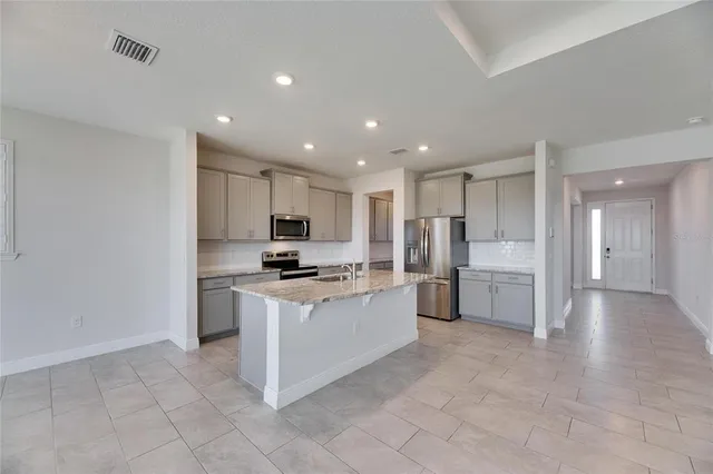 a view of a kitchen with kitchen island stainless steel appliances refrigerator stove microwave and cabinets
