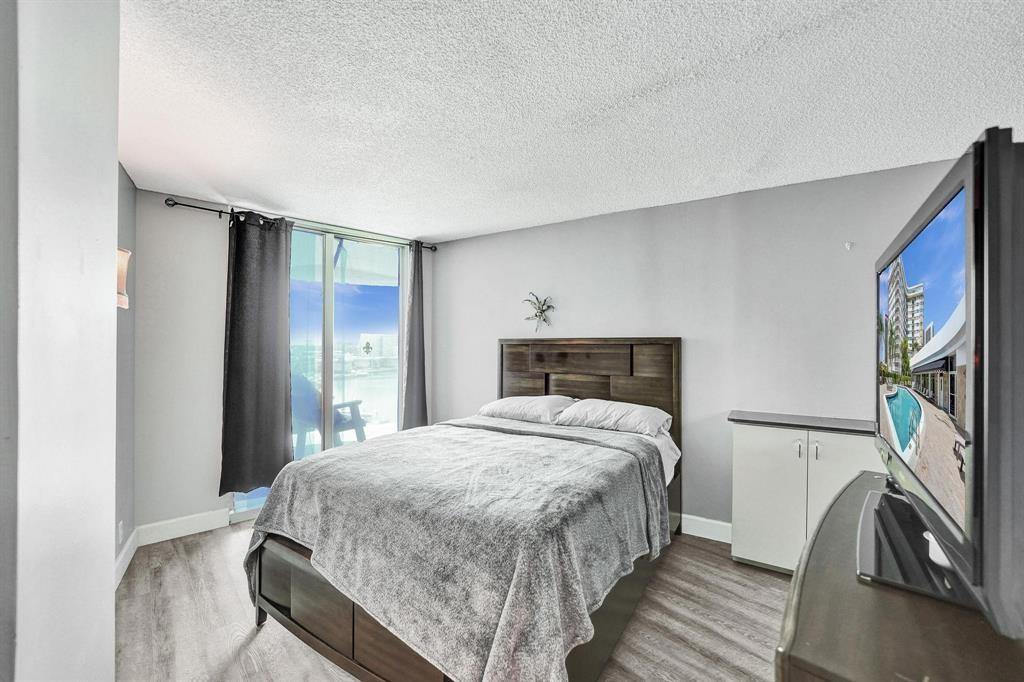 100 Golden Isles Drive, Unit 815 Hallandale Beach, FL 33009 - Photo 13 of 42 a bedroom with a bed and a flat tv screen on a dresser