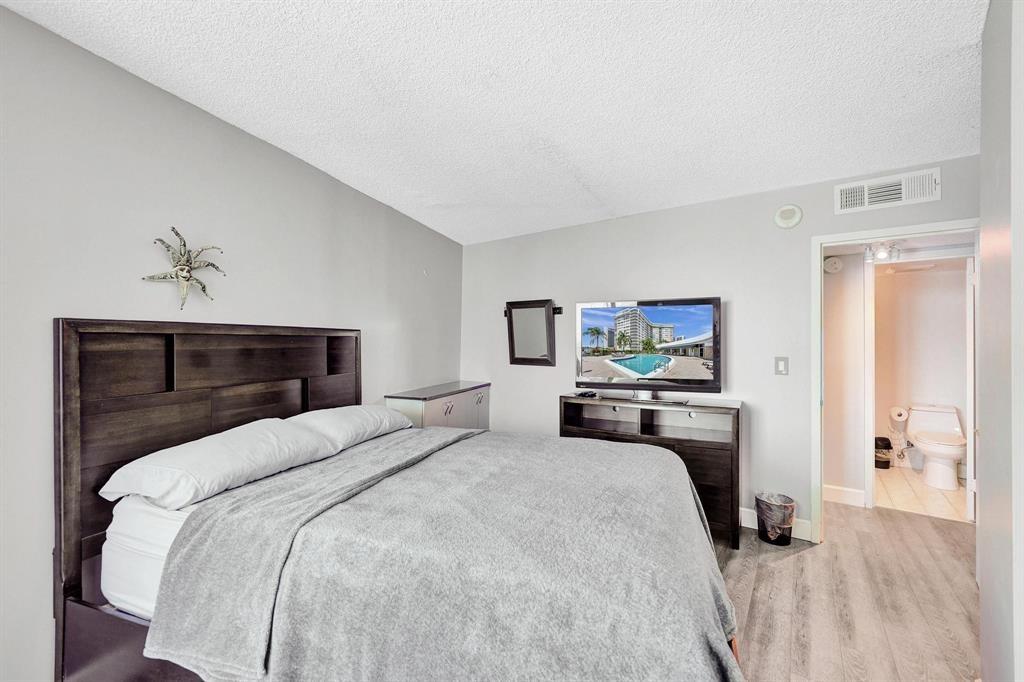 100 Golden Isles Drive, Unit 815 Hallandale Beach, FL 33009 - Photo 14 of 42 a bedroom with a large bed and a chandelier